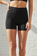 Black high-waisted shorts worn by a person on a beige background