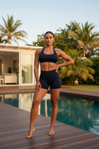 Person wearing a black sports bra and shorts on a light gray background